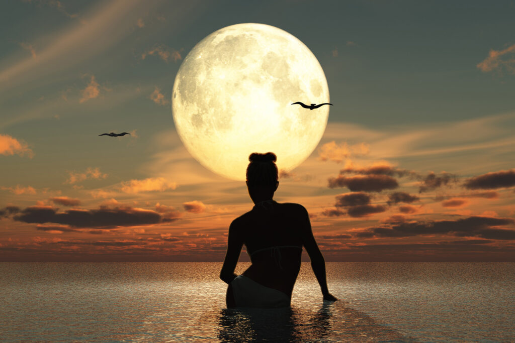 Silhouette einer sitzenden Frau im Wasser bei Vollmond