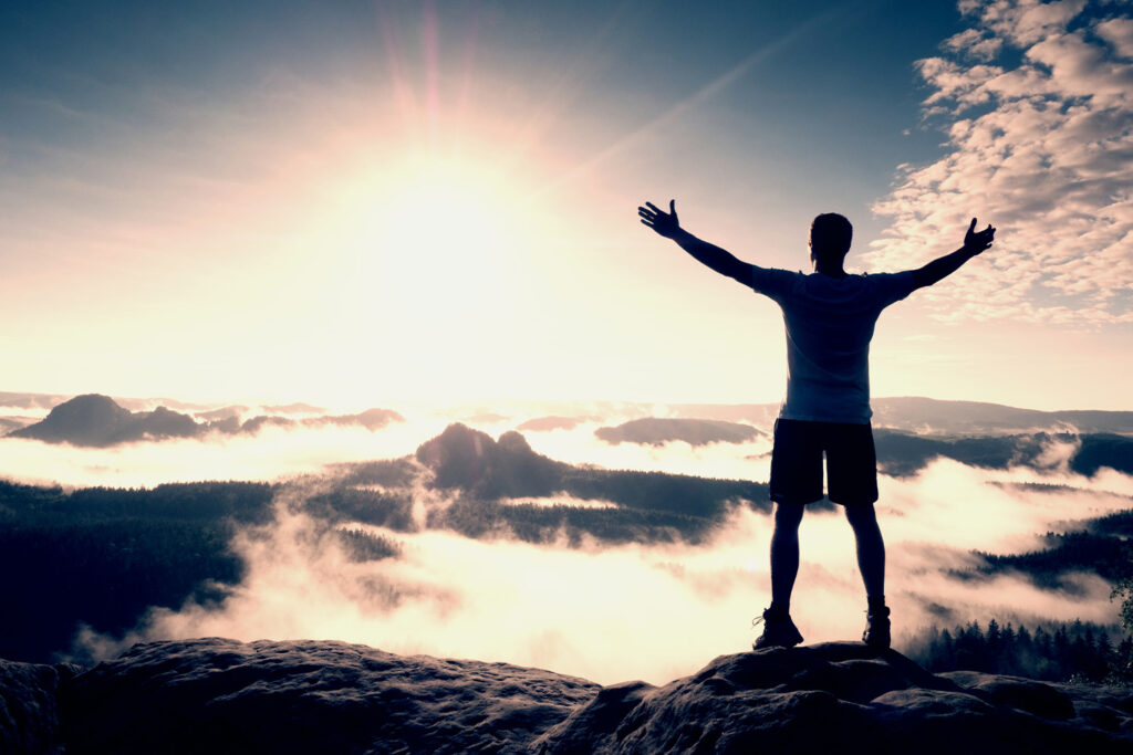 Sportler steht auf dem Berg oben und genießt die Aussicht