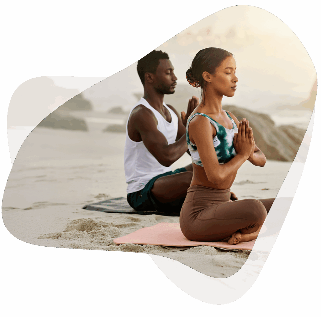 2 Personen sitzen ruhig am Strand und meditieren